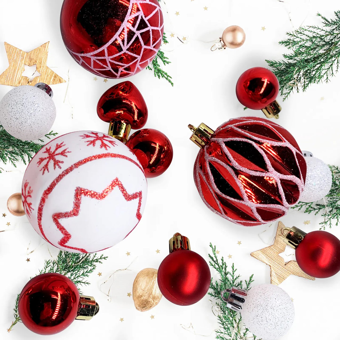 Collection of red and white Christmas ornaments on a white background with greenery.