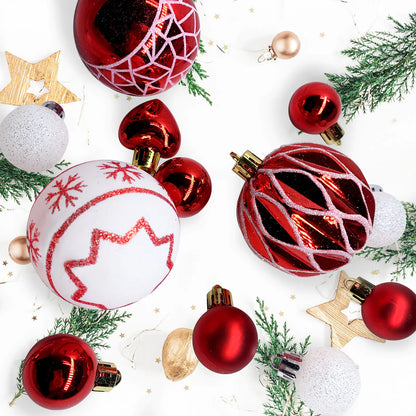 Collection of red and white Christmas ornaments on a white background with greenery.
