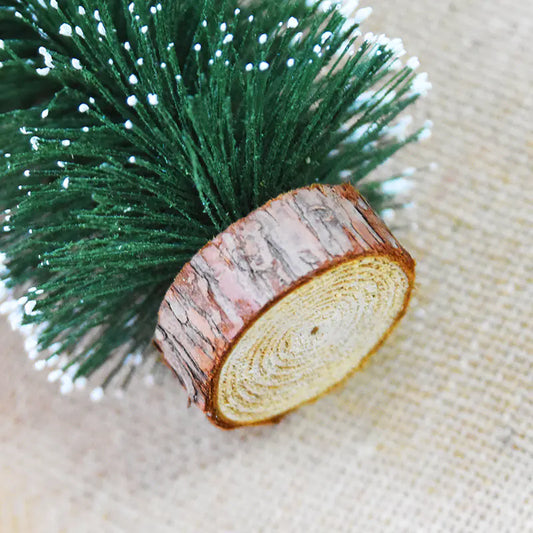 Decorative item with green pine-like material and a wooden log slice on a textured beige background