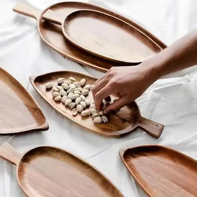 Wooden trays on a white surface with a hand placing beans on one of them.