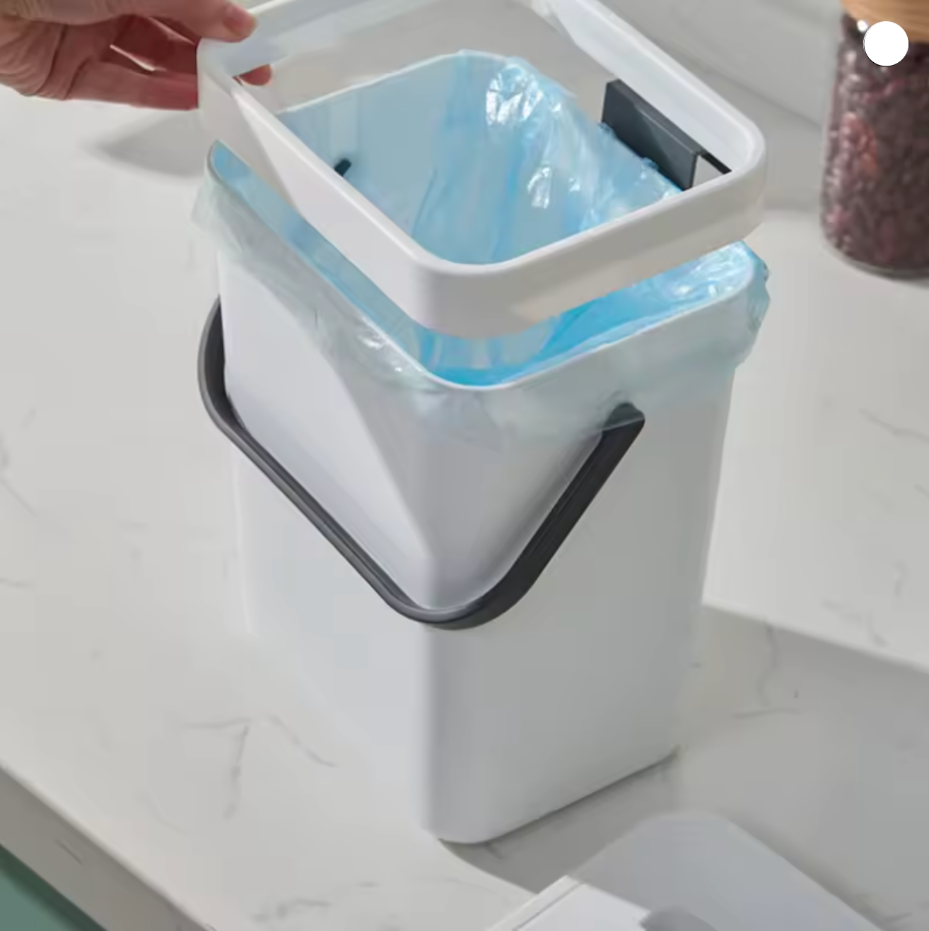 White trash bin with a blue liner on a white surface
