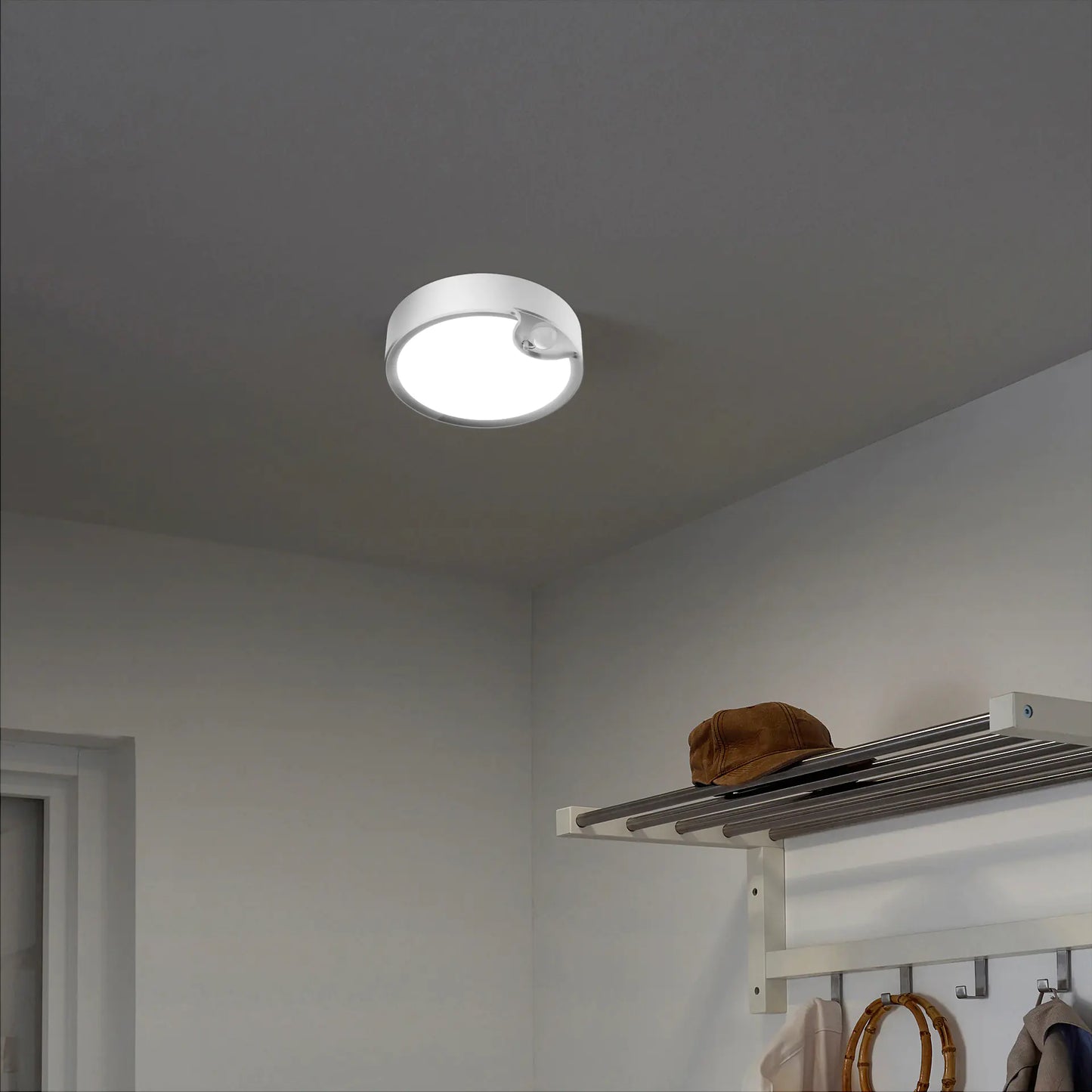 Ceiling light fixture in a room with a coat rack and hat.