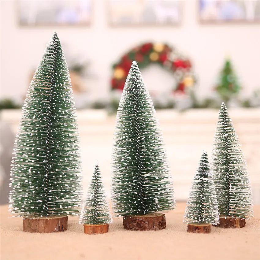 Set of small snow-covered Christmas trees on wooden bases in a festive setting.