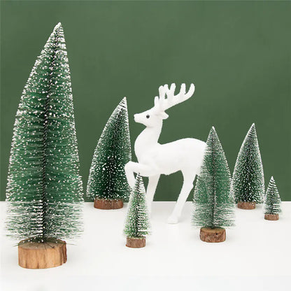 White deer figure standing among miniature snow-covered trees on a white surface with a green background